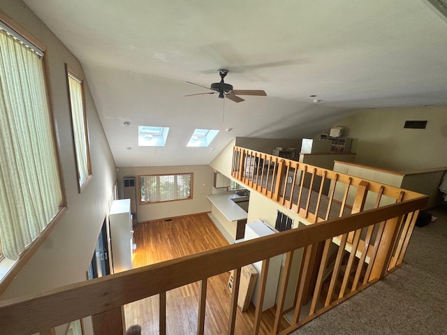 stairway with a skylight, lofted ceiling, a ceiling fan, and wood finished floors