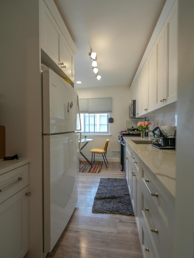 2725 E 65th St, Brooklyn, NY 11234 - kitchen featuring white cabinetry, stainless steel appliances, light wood-type flooring, and light stone countertops