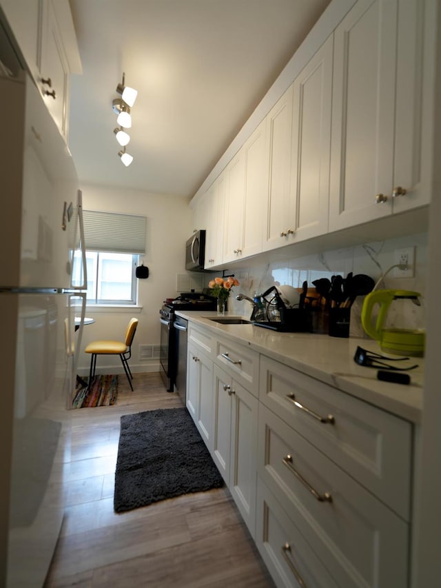 2725 E 65th St, Brooklyn, NY 11234 - kitchen featuring stainless steel appliances, white cabinetry, and light wood-style floors