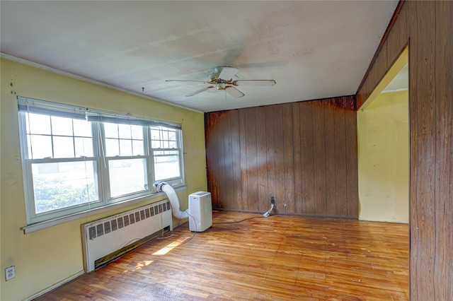 1435 Peters Blvd, Bay Shore, NY 11706 - spare room with wood walls, radiator heating unit, a ceiling fan, light wood-style flooring, and ornamental molding