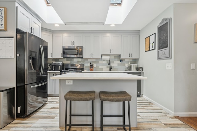 76 Cadman Ave, Babylon, NY 11702 - kitchen featuring stainless steel appliances, recessed lighting, light countertops, a breakfast bar area, and a skylight
