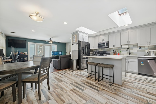 76 Cadman Ave, Babylon, NY 11702 - kitchen with appliances with stainless steel finishes, a skylight, tasteful backsplash, open floor plan, and light countertops