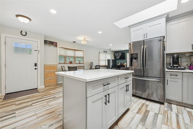 76 Cadman Ave, Babylon, NY 11702 - kitchen featuring stainless steel fridge with ice dispenser, light wood-style floors, light countertops, a center island, and recessed lighting