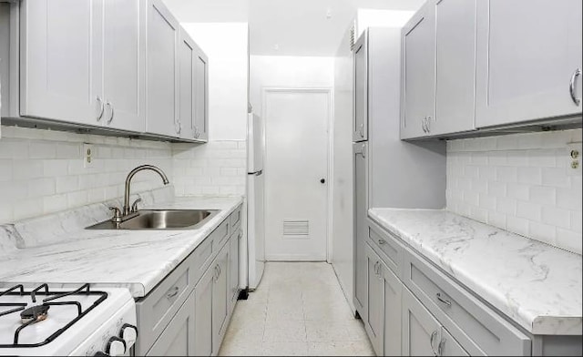 153-25 88th St Unit 1J, Howard Beach, NY 11414 - kitchen with decorative backsplash, freestanding refrigerator, gray cabinetry, and light stone counters