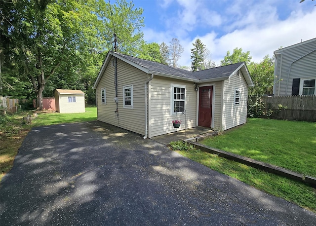1439 Ocean Ave, Bohemia, NY 11716 - view of front facade with asphalt driveway, a shed, and a shingled roof