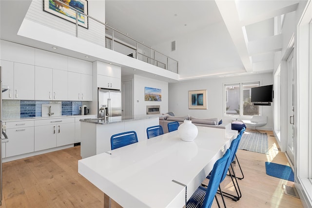 846 Dune Rd, Westhampton Dunes, NY 11978 - dining space with light wood-style flooring and a towering ceiling
