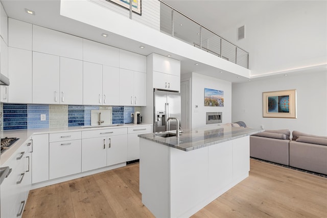 846 Dune Rd, Westhampton Dunes, NY 11978 - kitchen with a high ceiling, open floor plan, appliances with stainless steel finishes, light wood-style flooring, and white cabinetry