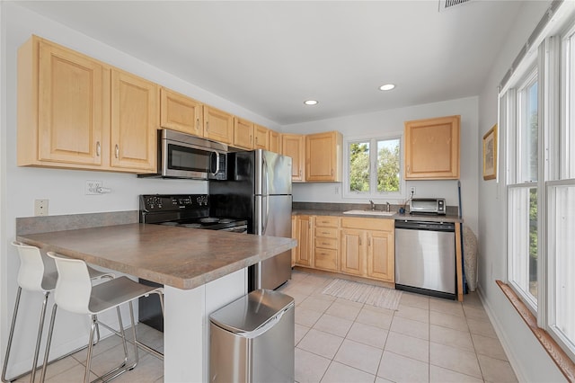 846 Dune Rd, Westhampton Dunes, NY 11978 - kitchen with light brown cabinets, a peninsula, appliances with stainless steel finishes, recessed lighting, and light tile patterned flooring