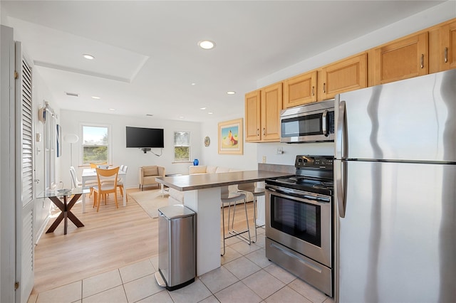 846 Dune Rd, Westhampton Dunes, NY 11978 - kitchen featuring appliances with stainless steel finishes, a breakfast bar area, dark countertops, light tile patterned floors, and recessed lighting