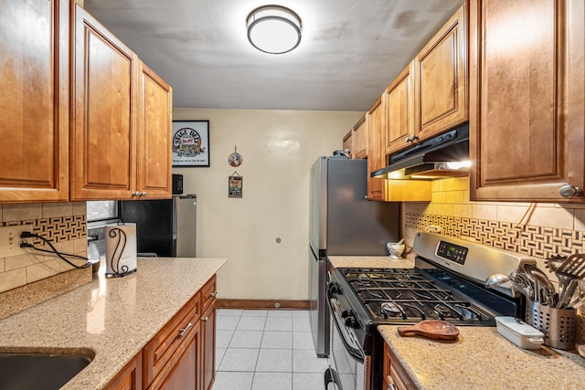 7910 34th Ave Unit 4J, Jackson Heights, NY 11372 - kitchen with stainless steel gas range oven, under cabinet range hood, light tile patterned floors, light stone countertops, and backsplash