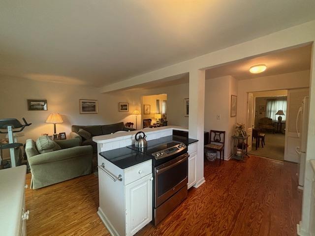 89 Hampton Ave, Albertson, NY 11507 - kitchen featuring stainless steel range with electric cooktop, dark wood-style floors, open floor plan, white cabinetry, and a peninsula