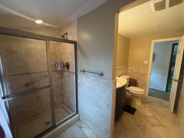 89 Hampton Ave, Albertson, NY 11507 - bathroom with tile walls, a shower stall, vanity, and wainscoting