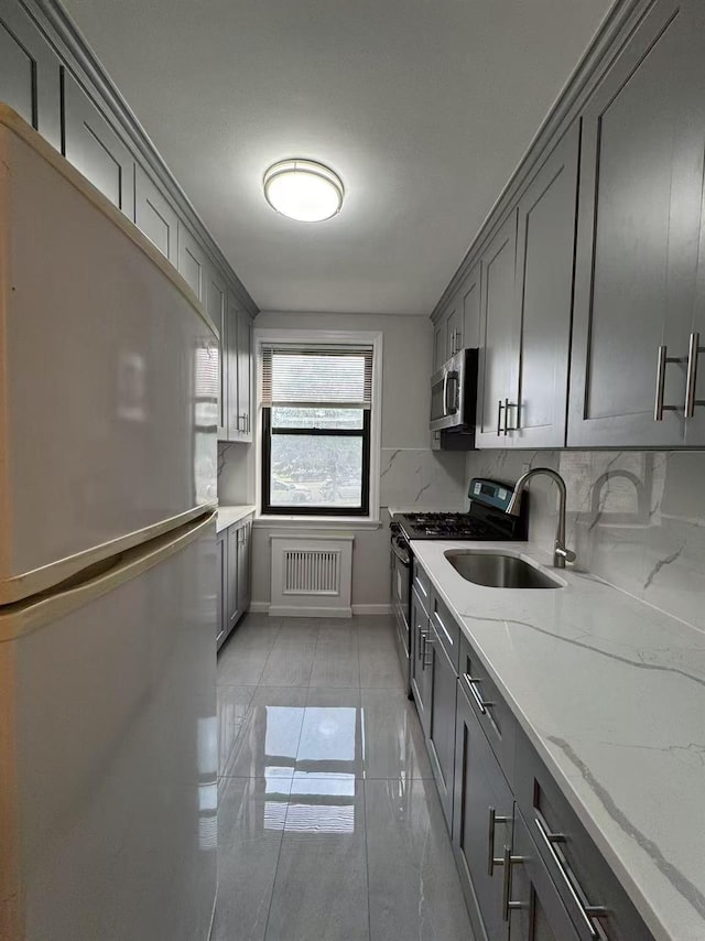 138-18 28th Rd Unit 1F, Flushing, NY 11354 - kitchen with freestanding refrigerator, gray cabinets, range with gas stovetop, light stone counters, and stainless steel microwave