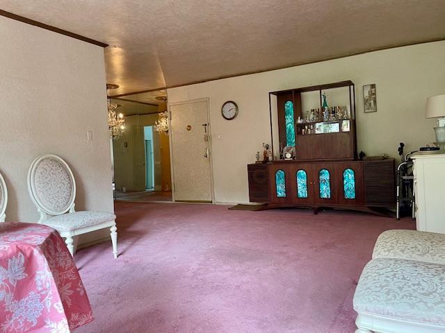 23-20 Bell Blvd Unit 2D, Bayside, NY 11360 - living area with carpet floors, a chandelier, and a textured ceiling