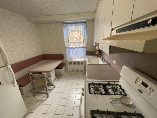 23-20 Bell Blvd Unit 2D, Bayside, NY 11360 - kitchen featuring white appliances, wallpapered walls, under cabinet range hood, radiator, and light tile patterned flooring
