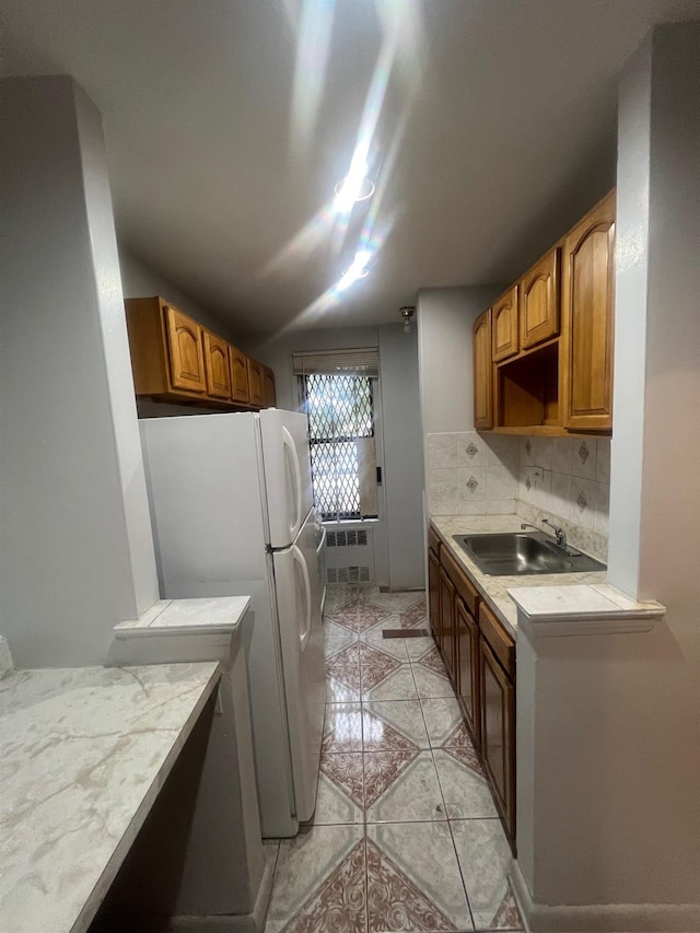 285 E 35th St Unit 2D, Brooklyn, NY 11203 - kitchen featuring light tile patterned floors, freestanding refrigerator, radiator heating unit, tasteful backsplash, and brown cabinets