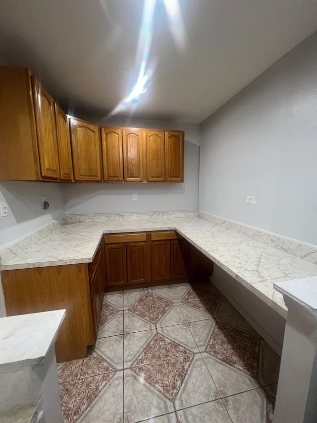 285 E 35th St Unit 2D, Brooklyn, NY 11203 - kitchen with brown cabinetry, light countertops, and light tile patterned flooring