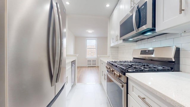 66-15 Thornton Pl Unit 6S, Rego Park, NY 11374 - kitchen featuring stainless steel appliances, white cabinets, light stone counters, decorative backsplash, and recessed lighting