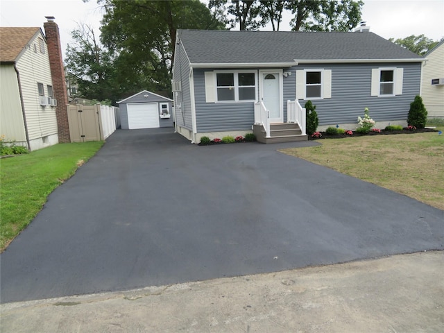 118 Muncy Ave, West Babylon, NY 11704 - ranch-style home featuring asphalt driveway, a garage, an outbuilding, roof with shingles, and a front yard
