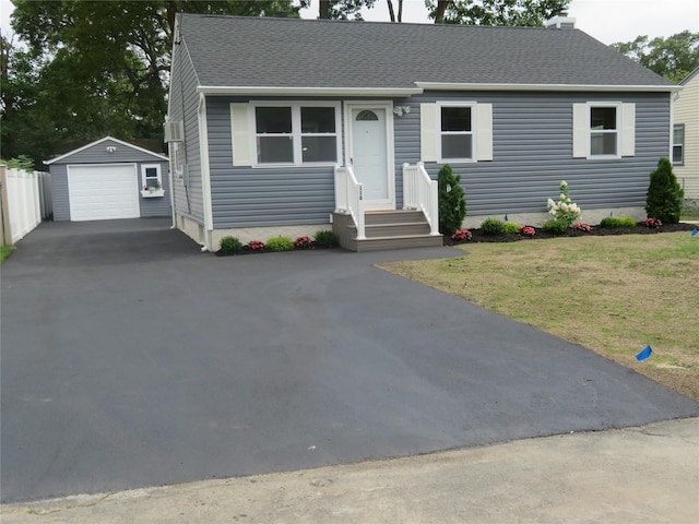 118 Muncy Ave, West Babylon, NY 11704 - view of front of home with asphalt driveway, a detached garage, roof with shingles, an outbuilding, and a front lawn