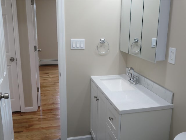 118 Muncy Ave, West Babylon, NY 11704 - half bathroom with vanity, wood finished floors, and a baseboard radiator