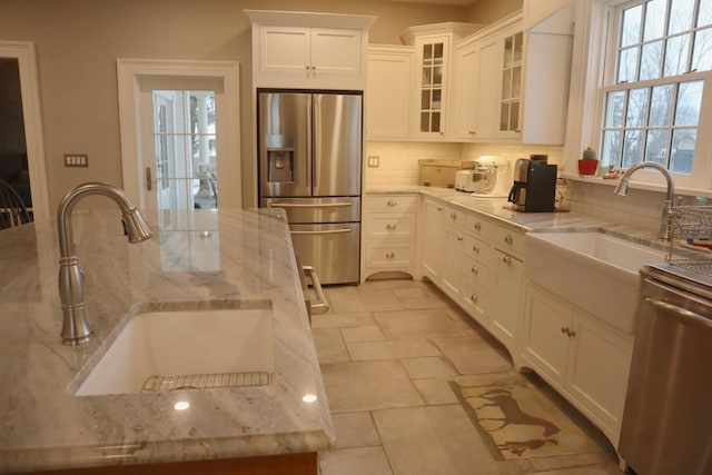 kitchen with light stone counters, sink, white cabinetry, and appliances with stainless steel finishes