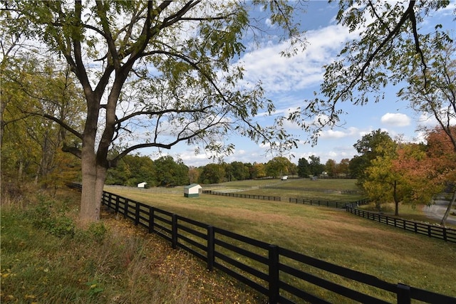 view of community with a storage shed, a rural view, and a lawn