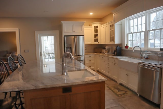 kitchen with sink, a breakfast bar area, appliances with stainless steel finishes, white cabinetry, and light stone counters