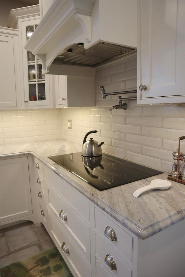 kitchen with premium range hood, backsplash, light stone counters, and white cabinets