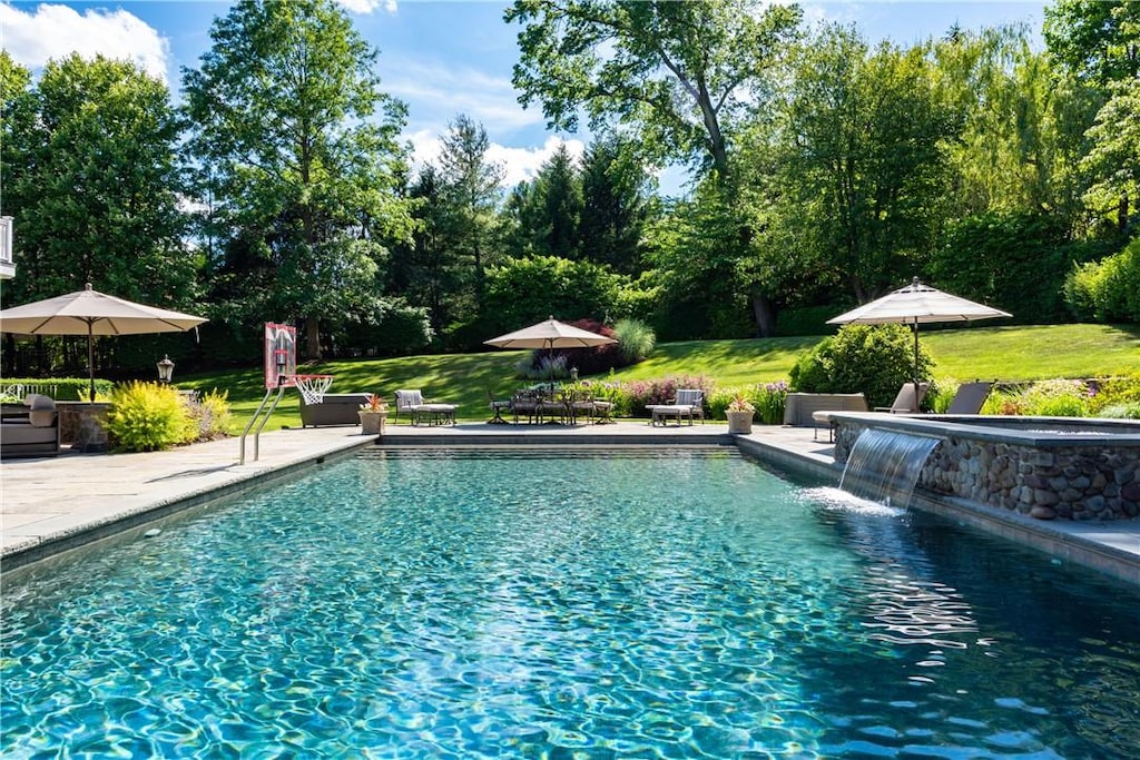 view of pool with pool water feature, a patio area, and a lawn