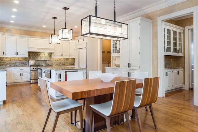 dining space with crown molding and light wood-type flooring