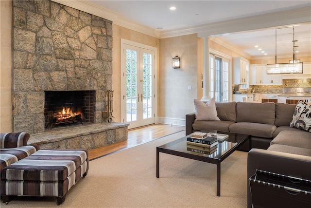 living room with a fireplace, french doors, light wood-type flooring, and ornamental molding