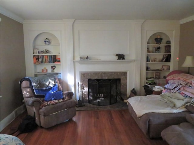 living room with built in features, wood-type flooring, and ornamental molding