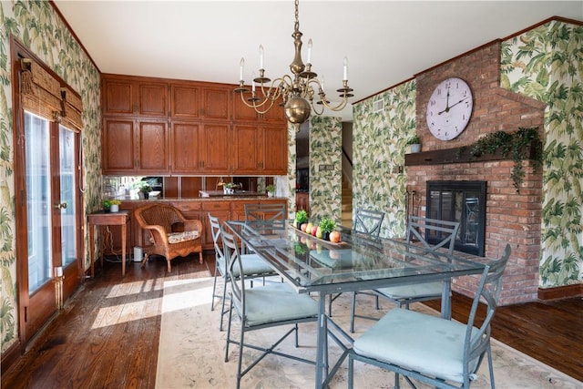 dining area featuring french doors, wood-type flooring, a notable chandelier, and a brick fireplace