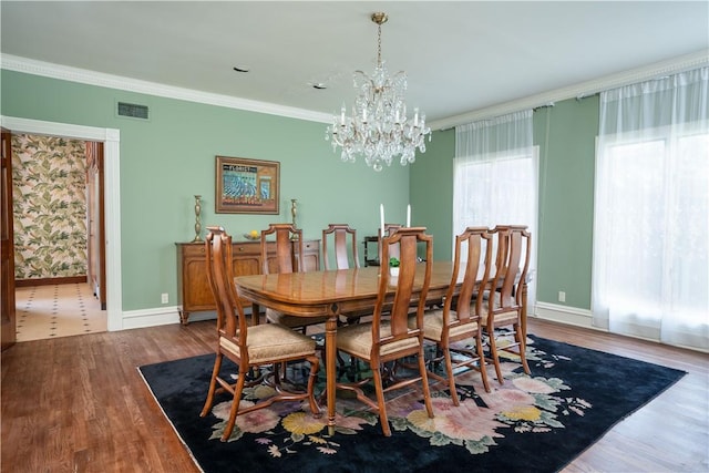 dining area with hardwood / wood-style flooring, crown molding, and an inviting chandelier