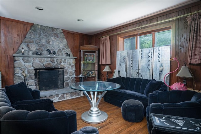 living room with a fireplace, hardwood / wood-style flooring, and wooden walls