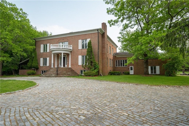 view of front of home featuring a balcony and a front lawn