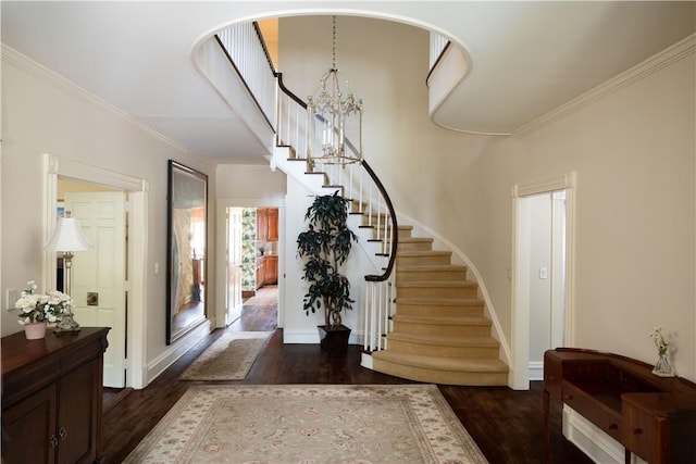 foyer with ornamental molding, dark wood-type flooring, and an inviting chandelier