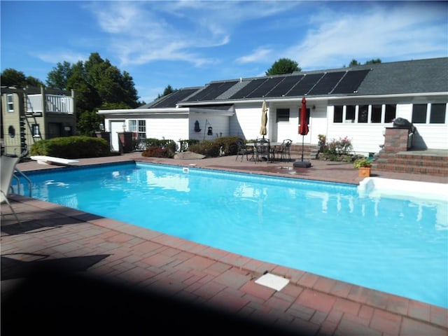 view of pool featuring a diving board and a patio