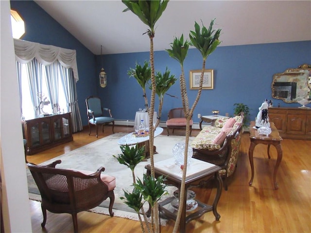 living area featuring vaulted ceiling, a baseboard radiator, and light hardwood / wood-style flooring