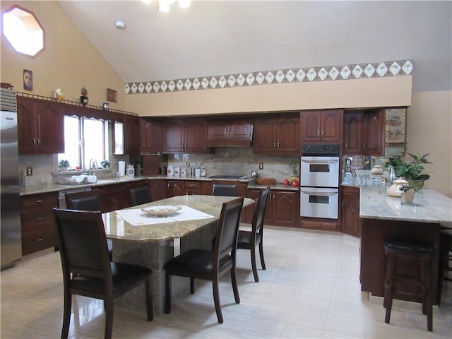 kitchen with white double oven, high vaulted ceiling, dishwasher, a center island, and built in refrigerator