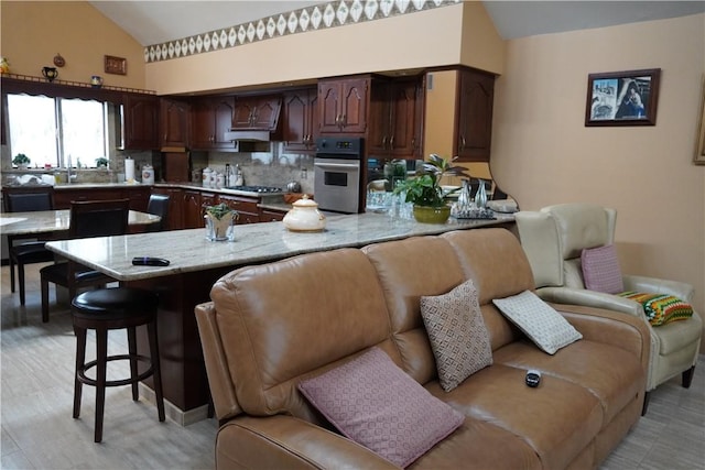 kitchen with kitchen peninsula, appliances with stainless steel finishes, a kitchen breakfast bar, backsplash, and dark brown cabinetry