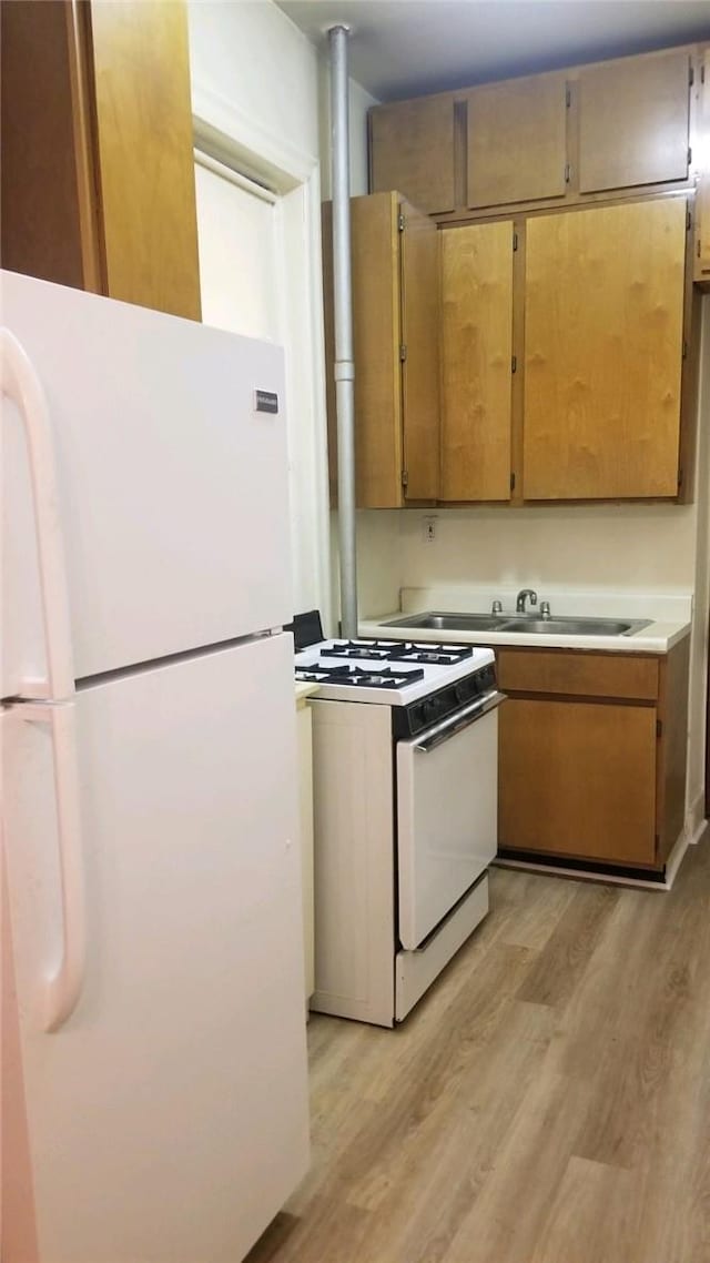 kitchen featuring sink, white appliances, and light wood-type flooring