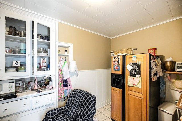 kitchen featuring wooden walls, ornamental molding, light tile patterned flooring, white cabinetry, and fridge with ice dispenser