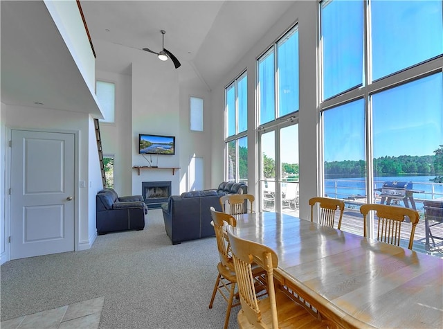 dining room with ceiling fan, light colored carpet, and high vaulted ceiling