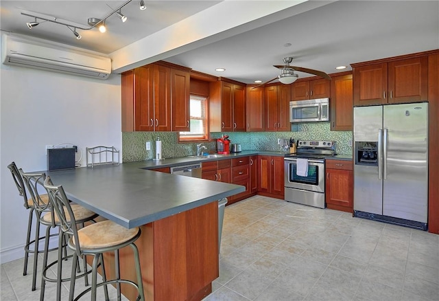 kitchen with ceiling fan, a wall unit AC, backsplash, a kitchen bar, and appliances with stainless steel finishes