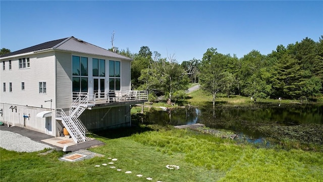 back of house with a lawn and a water view