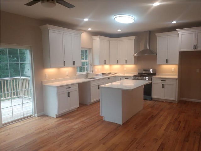 kitchen featuring white cabinetry, stainless steel range oven, a kitchen island, and wall chimney range hood