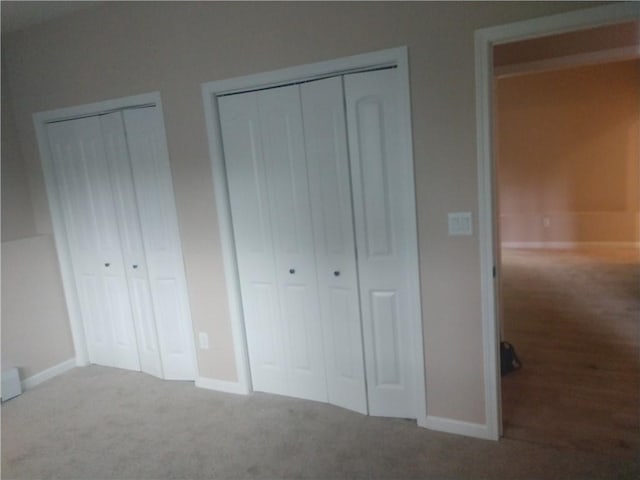 unfurnished bedroom featuring multiple closets and carpet floors