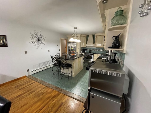 kitchen with custom exhaust hood, baseboard heating, decorative light fixtures, a kitchen island, and wood-type flooring